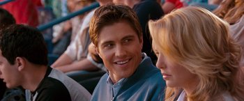 Movie still from “The Ugly Truth” (2009), directed by Robert Luketic – A man and a woman sitting in a crowd of people; Close Up shot, Over the shoulder angle