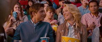 Movie still from “The Ugly Truth” (2009), directed by Robert Luketic – A man and a woman sitting next to each other at an event; Medium shot, Over the shoulder angle
