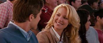 Movie still from “The Ugly Truth” (2009), directed by Robert Luketic – A woman smiles at the camera as a man looks on; Close Up shot, Over the shoulder angle