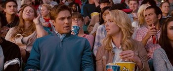 Movie still from “The Ugly Truth” (2009), directed by Robert Luketic – A man and a woman sitting next to each other in front of a crowd; Medium shot, Over the shoulder angle