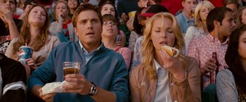 Movie still from “The Ugly Truth” (2009), directed by Robert Luketic – A man and a woman sitting next to each other in front of a crowd; Medium shot, Over the shoulder angle