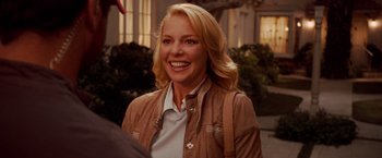 Movie still from “The Ugly Truth” (2009), directed by Robert Luketic – A woman smiling for the camera while wearing a brown jacket; Close Up shot, Over the shoulder angle
