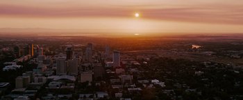 Movie still from “The Ugly Truth” (2009), directed by Robert Luketic – An aerial view of a city at sunset with the sun setting; Extreme Wide shot, High angle
