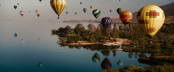 Movie still from “The Ugly Truth” (2009), directed by Robert Luketic – A group of hot air balloons flying over a body of water; Extreme Wide shot, High angle