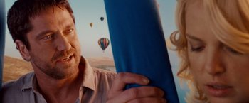 Movie still from “The Ugly Truth” (2009), directed by Robert Luketic – A man holding a book in front of balloons; Close Up shot, Over the shoulder angle