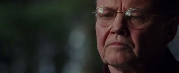 Movie still from “Enemy of the State” (1998), directed by Tony Scott – An older man wearing glasses and a red shirt; Close Up shot, Over the shoulder angle