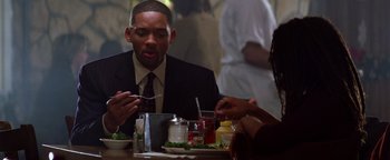 Movie still from “Enemy of the State” (1998), directed by Tony Scott – Two people sitting at a table with a plate of food; Close Up shot, Over the shoulder angle