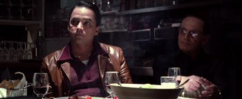 Movie still from “Enemy of the State” (1998), directed by Tony Scott – A man sitting at a table with a plate of food; Close Up shot, Over the shoulder angle