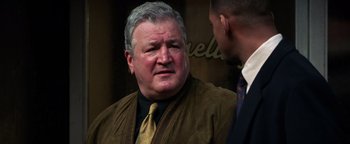 Movie still from “Enemy of the State” (1998), directed by Tony Scott – A man in a brown jacket and a man in a yellow tie; Close Up shot, Over the shoulder angle