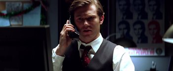 Movie still from “Enemy of the State” (1998), directed by Tony Scott – A man in a vest and tie talking on a cell phone; Close Up shot, Low angle