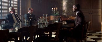 Movie still from “Enemy of the State” (1998), directed by Tony Scott – A group of people sitting at a table in a room; Wide shot, Low angle