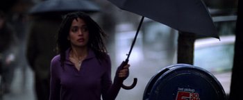 Movie still from “Enemy of the State” (1998), directed by Tony Scott – A woman holding an umbrella while standing next to a fire hydrant; Medium shot, Low angle