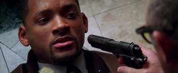 Movie still from “Enemy of the State” (1998), directed by Tony Scott – A person holding a gun; Close Up shot, High angle
