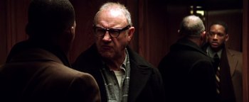 Movie still from “Enemy of the State” (1998), directed by Tony Scott – An older man wearing glasses and a jacket; Close Up shot, Over the shoulder angle