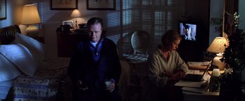Movie still from “Enemy of the State” (1998), directed by Tony Scott – A man and a woman are sitting in a living room; Medium shot, High angle