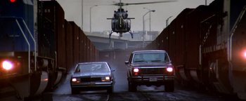 Movie still from “Enemy of the State” (1998), directed by Tony Scott – A helicopter is flying over two cars in a tunnel; Wide shot, Low angle