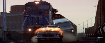 Movie still from “Enemy of the State” (1998), directed by Tony Scott – A car on fire on the side of the road; Wide shot, Low angle