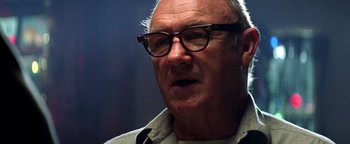 Movie still from “Enemy of the State” (1998), directed by Tony Scott – An older man wearing glasses and a white shirt; Close Up shot, Low angle