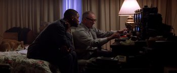 Movie still from “Enemy of the State” (1998), directed by Tony Scott – Two men sitting at a table looking at something on a computer screen; Medium shot, Low angle