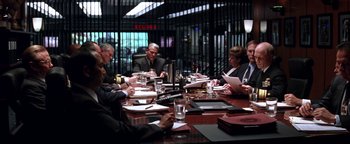 Movie still from “Enemy of the State” (1998), directed by Tony Scott – A group of people sitting at a table with papers; Wide shot, Over the shoulder angle
