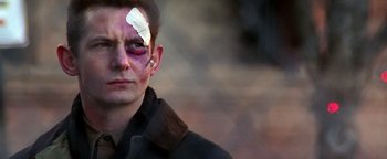 Movie still from “Enemy of the State” (1998), directed by Tony Scott – A man with a bandage on his head and face; Close Up shot, Over the shoulder angle