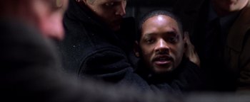 Movie still from “Enemy of the State” (1998), directed by Tony Scott – Two men in black jackets one of whom has a black shirt on; Close Up shot, Over the shoulder angle