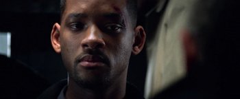 Movie still from “Enemy of the State” (1998), directed by Tony Scott – A person with a scar on his face; Close Up shot, Over the shoulder angle