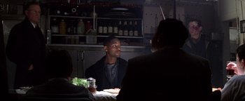 Movie still from “Enemy of the State” (1998), directed by Tony Scott – A man sitting at a table in front of another man; Medium shot, Over the shoulder angle