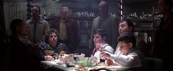 Movie still from “Enemy of the State” (1998), directed by Tony Scott – A group of people sitting around a table eating; Medium shot, Over the shoulder angle