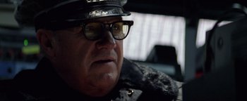 Movie still from “Enemy of the State” (1998), directed by Tony Scott – An older man wearing a hat and glasses in a car; Close Up shot, Low angle
