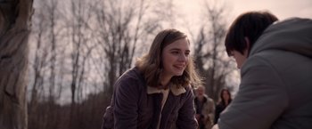 Movie still from “The Unholy” (2021), directed by Evan Spiliotopoulos – A young woman smiles while sitting in front of trees; Medium shot, Over the shoulder angle