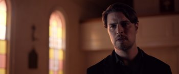 Movie still from “The Unholy” (2021), directed by Evan Spiliotopoulos – A person wearing a suit; Close Up shot, Low angle