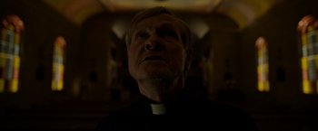 Movie still from “The Unholy” (2021), directed by Evan Spiliotopoulos – A man wearing a priest's outfit looking up; Close Up shot, Low angle