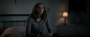 Movie still from “The Unholy” (2021), directed by Evan Spiliotopoulos – A woman sitting in front of a lamp in a dark room; Medium shot, Over the shoulder angle