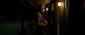 Movie still from “The Unholy” (2021), directed by Evan Spiliotopoulos – A man standing in the dark holding a banana; Medium shot, Over the shoulder angle