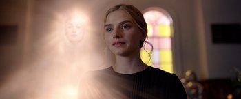 Movie still from “The Unholy” (2021), directed by Evan Spiliotopoulos – A beautiful young woman standing in front of a stained glass window; Close Up shot, Low angle