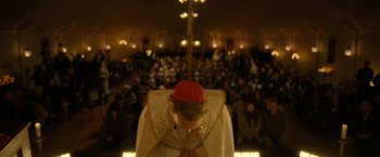 Movie still from “The Unholy” (2021), directed by Evan Spiliotopoulos – A man with a red hat is kneeling in front of a crowd; Medium shot, High angle