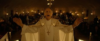 Movie still from “The Unholy” (2021), directed by Evan Spiliotopoulos – A man wearing a priest's outfit with a cross on his chest; Medium shot, Low angle