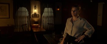 Movie still from “The Unholy” (2021), directed by Evan Spiliotopoulos – A woman standing at a table in a dark room; Medium shot, Over the shoulder angle