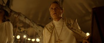 Movie still from “The Unholy” (2021), directed by Evan Spiliotopoulos – A man wearing a priest's outfit with a cross on it; Close Up shot, Low angle