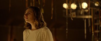 Movie still from “The Unholy” (2021), directed by Evan Spiliotopoulos – A woman standing in front of a wall with lights; Medium shot, Over the shoulder angle