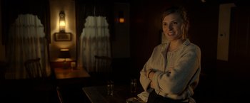 Movie still from “The Unholy” (2021), directed by Evan Spiliotopoulos – A woman sitting at a table in a dark room; Medium shot, Over the shoulder angle