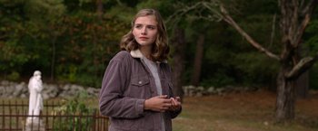 Movie still from “The Unholy” (2021), directed by Evan Spiliotopoulos – A woman in a brown jacket standing in the grass; Medium shot, Over the shoulder angle