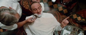Movie still from “The Untouchables” (1987), directed by Brian De Palma – A man shaves another man's beard while sitting in a barber shop; Close Up shot, High angle