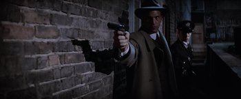 Movie still from “The Untouchables” (1987), directed by Brian De Palma – A man in a trench coat and hat holding a gun; Medium shot, Low angle