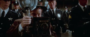 Movie still from “The Untouchables” (1987), directed by Brian De Palma – A man taking a picture of a police officer; Close Up shot, Over the shoulder angle