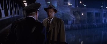 Movie still from “The Untouchables” (1987), directed by Brian De Palma – A man wearing a hat and a coat talking to another man wearing a hat and a coat; Medium shot, Over the shoulder angle