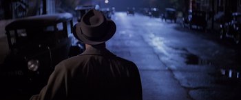 Movie still from “The Untouchables” (1987), directed by Brian De Palma – A man wearing a hat walking down a street; Close Up shot, Over the shoulder angle