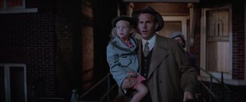 Movie still from “The Untouchables” (1987), directed by Brian De Palma – A man and a little girl are standing next to each other; Medium shot, Over the shoulder angle