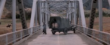 Movie still from “The Untouchables” (1987), directed by Brian De Palma – A man standing next to a truck on the side of a bridge; Wide shot, High angle